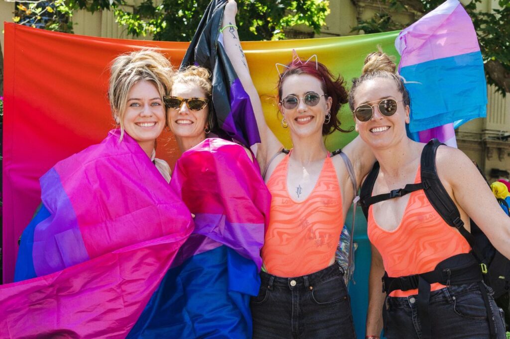 Queer women together holding a rainbow flag